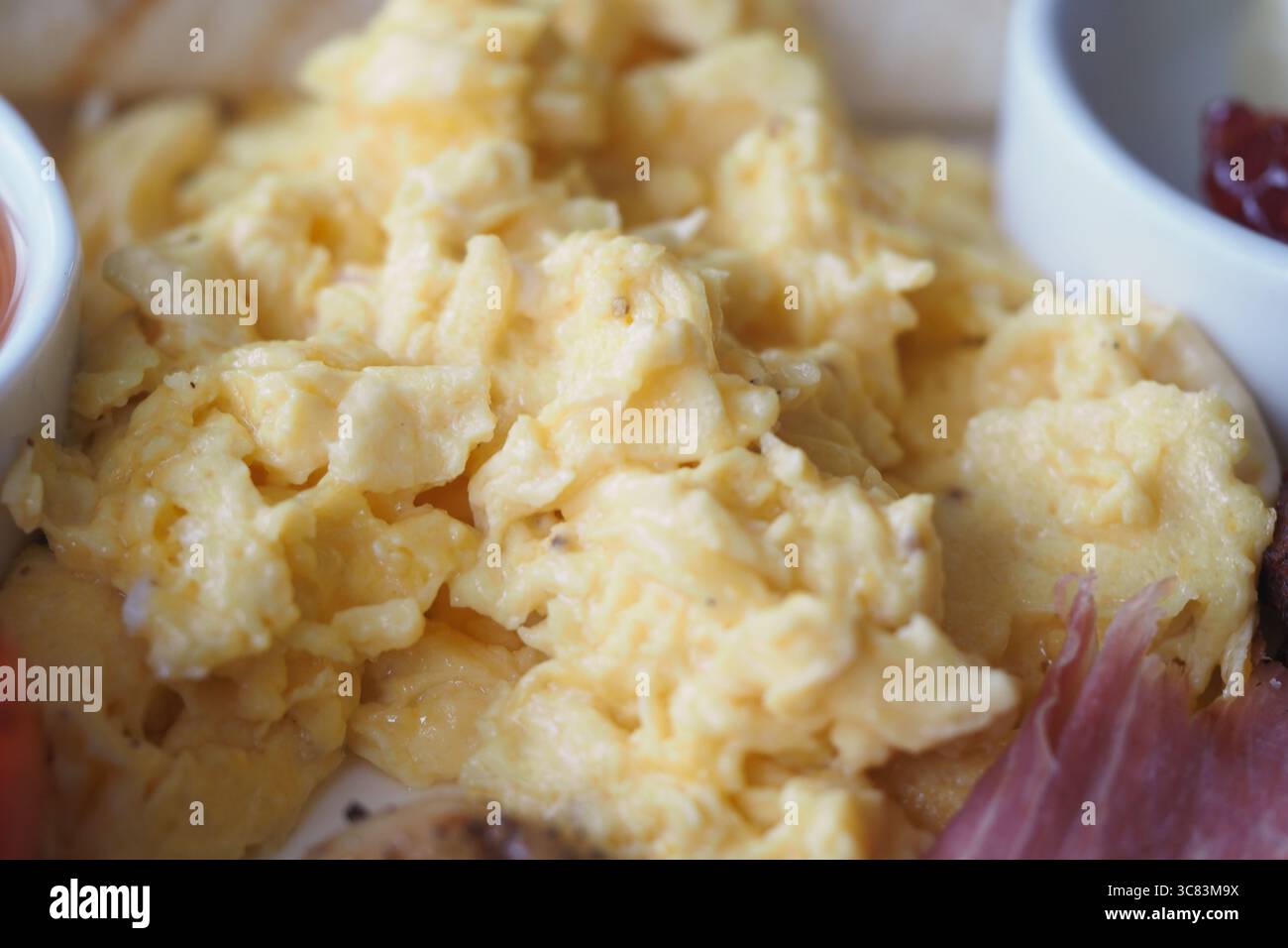 Delicious scrambled eggs served with breakfast sides Stock Photo