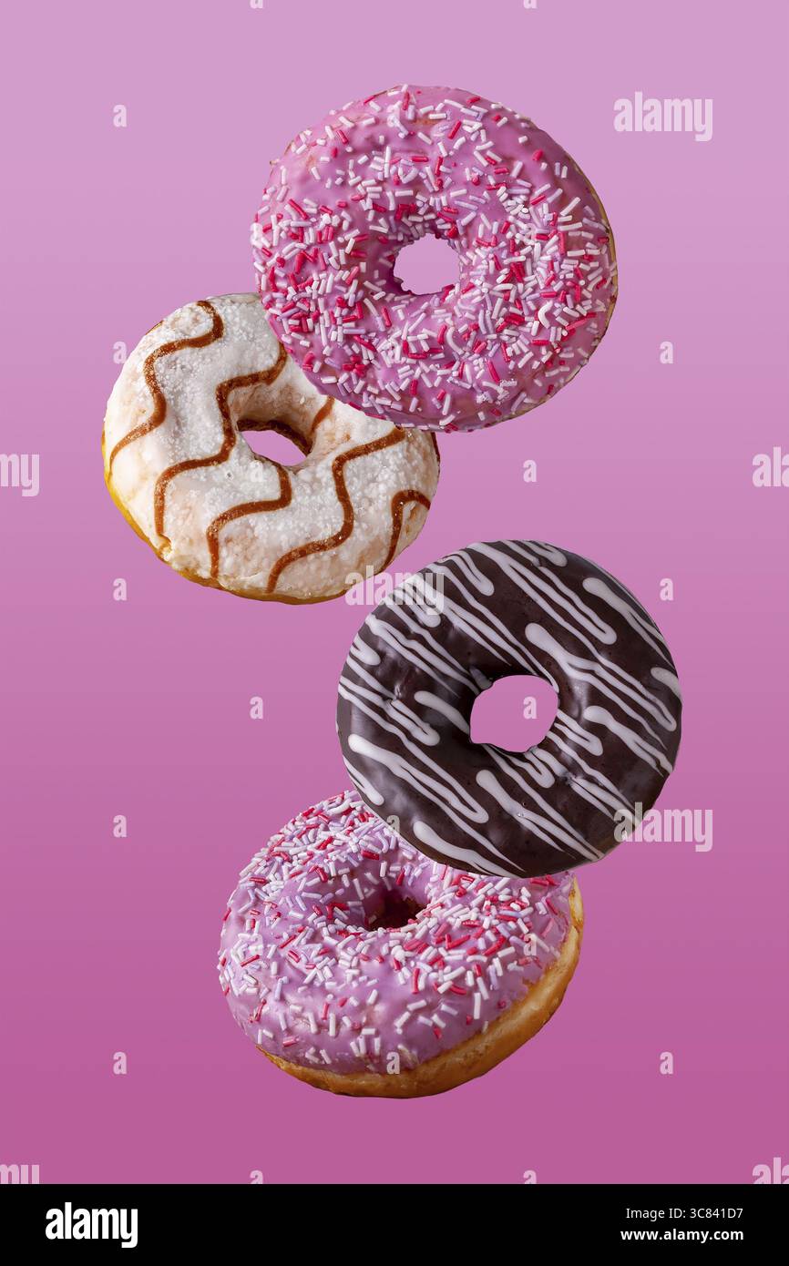 Donuts in chocolate and in sugar glaze fly on a pink background Stock Photo
