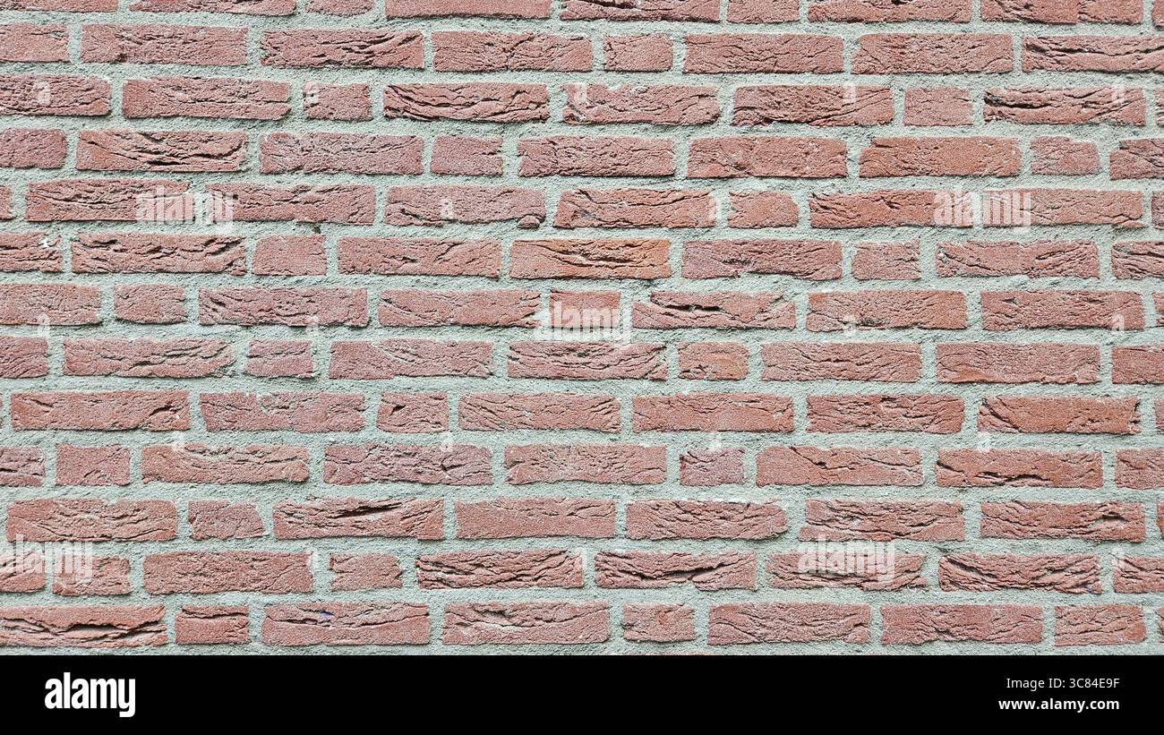 Detailed close-up of a red brick wall with rough surface texture and gray cement mortar. Ideal for background, construction, or architecture themes. - Smartphone Captured Stock Image