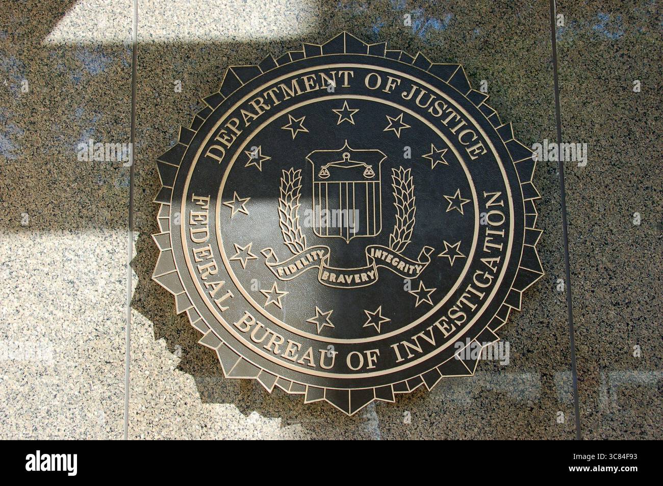 Bronze seal of the FBI, Department of Justice, featuring the motto “Fidelity, Bravery, Integrity,” mounted on a granite wall at headquarters Stock Photo