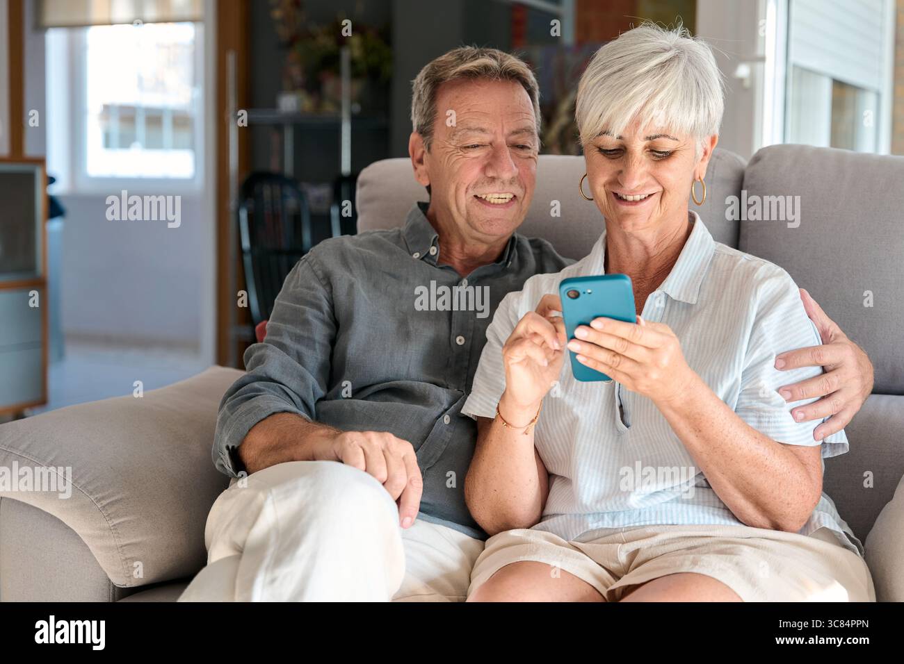 Happy senior couple using smartphone at home Stock Photo