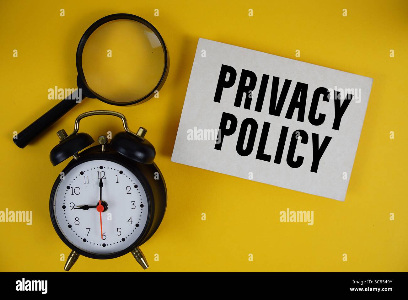 Privacy Policy text written on paper with magnifying glass and alarm clock on yellow background Stock Photo