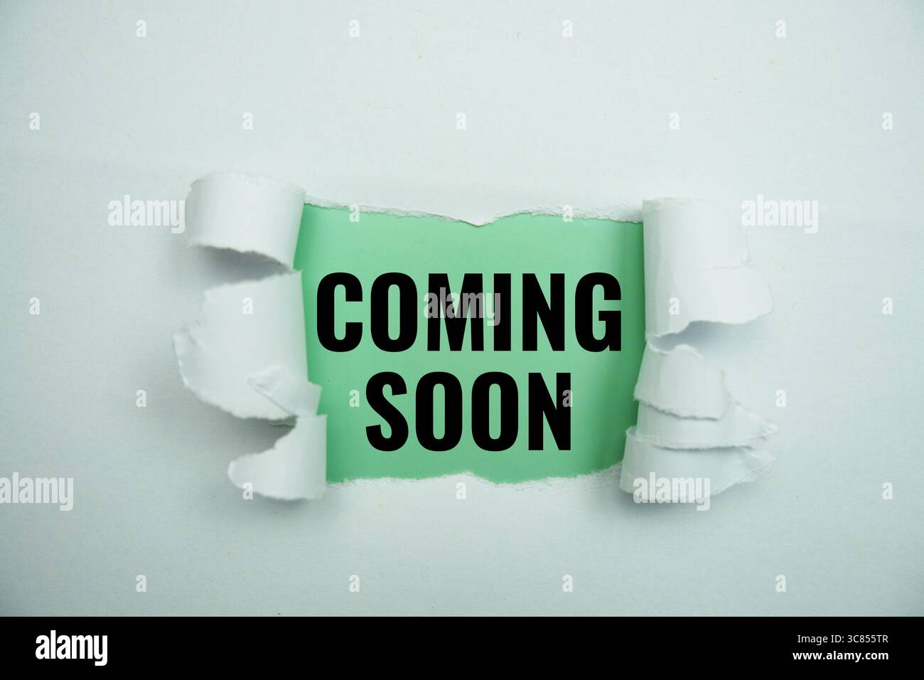 Coming soon message written on green paper with torn paper background Stock Photo