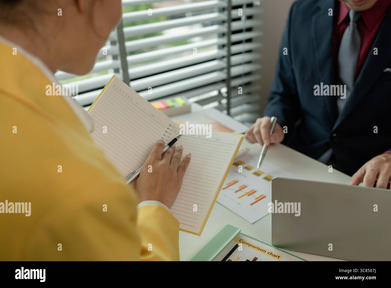 Two colleagues spend most of their time at workplace to meet deadlines, meeting between businessmen discussing first quarter sales, two employees work Stock Photo
