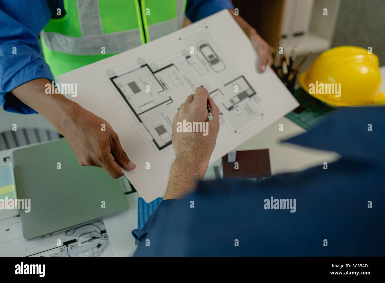 an engineer is in the office with his assistant, they are examining every detail in the blueprint, two architects are exchanging their idea to each ot Stock Photo