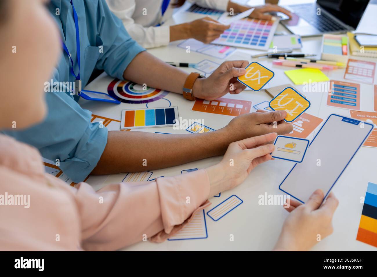 ux, ui, web and mobile app designers are discussing the look and feel of the website or app they are designing including color schemes and layouts to Stock Photo