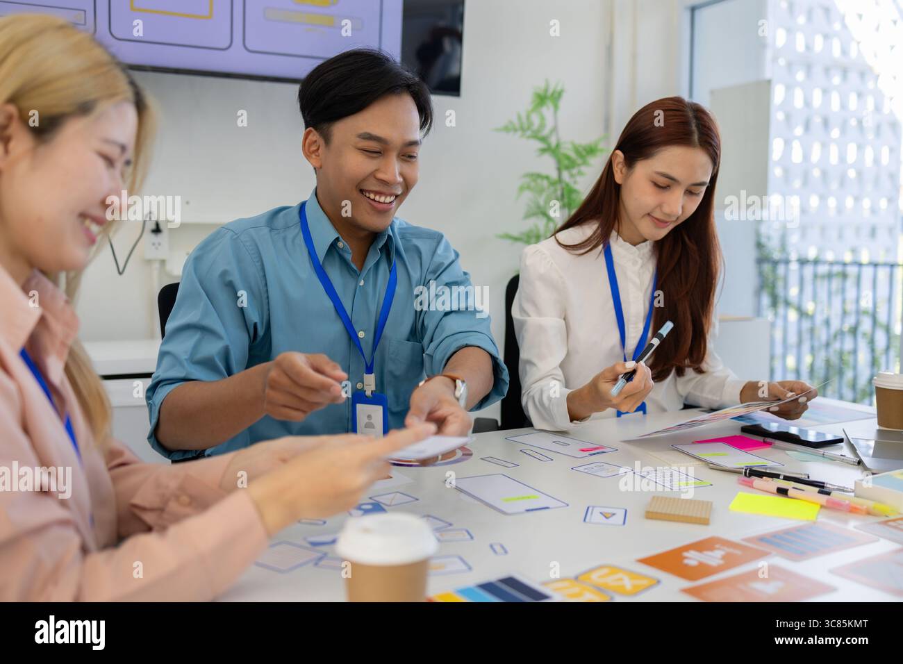 ux, ui, web and mobile app designers are discussing the look and feel of the website or app they are designing including color schemes and layouts to Stock Photo