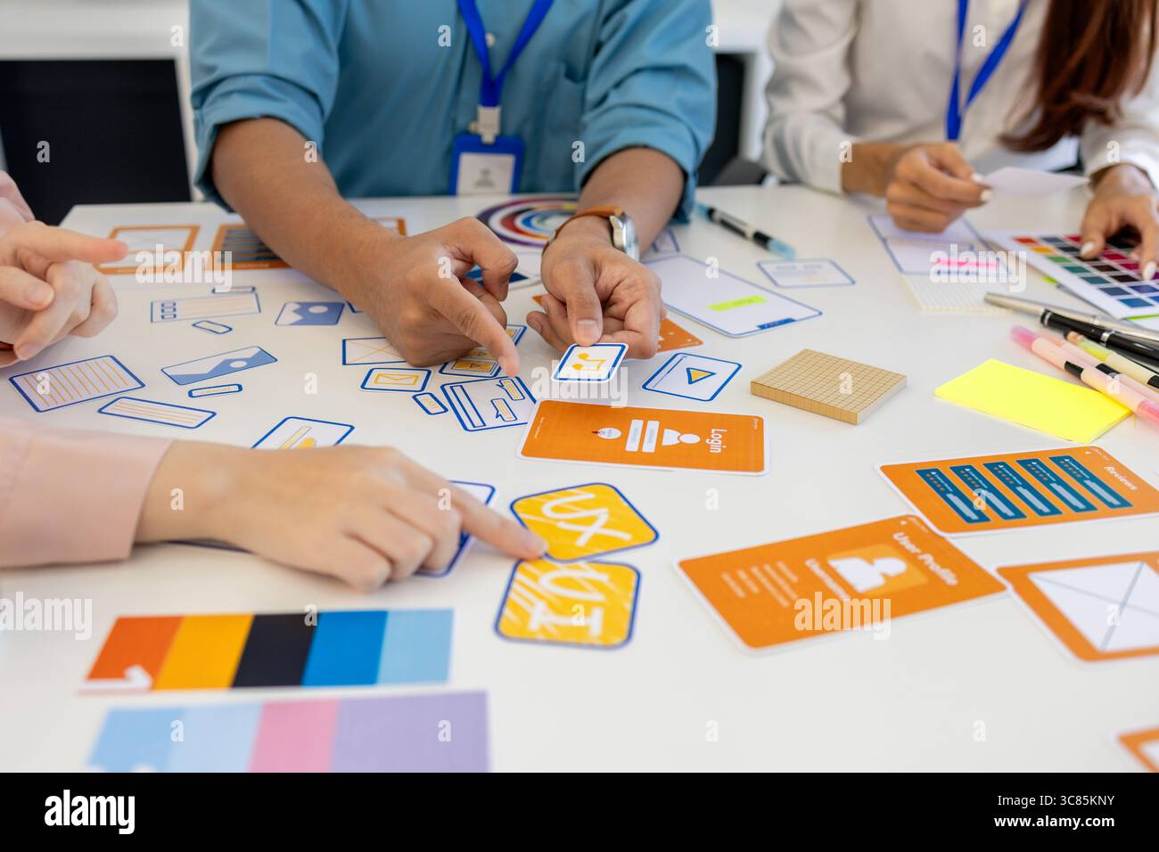 ux, ui, web and mobile app designers are discussing the look and feel of the website or app they are designing including color schemes and layouts to Stock Photo