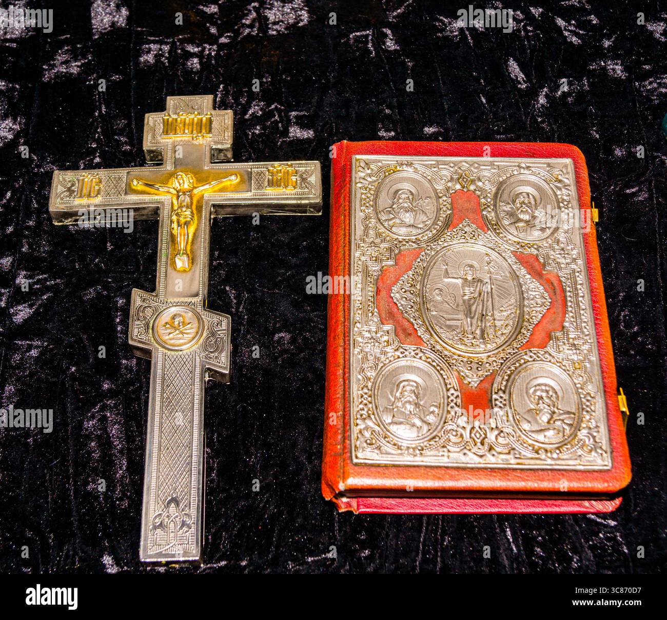 Beautiful religious cross and ornate book displayed on a dark velvet background during a spiritual gathering Stock Photo