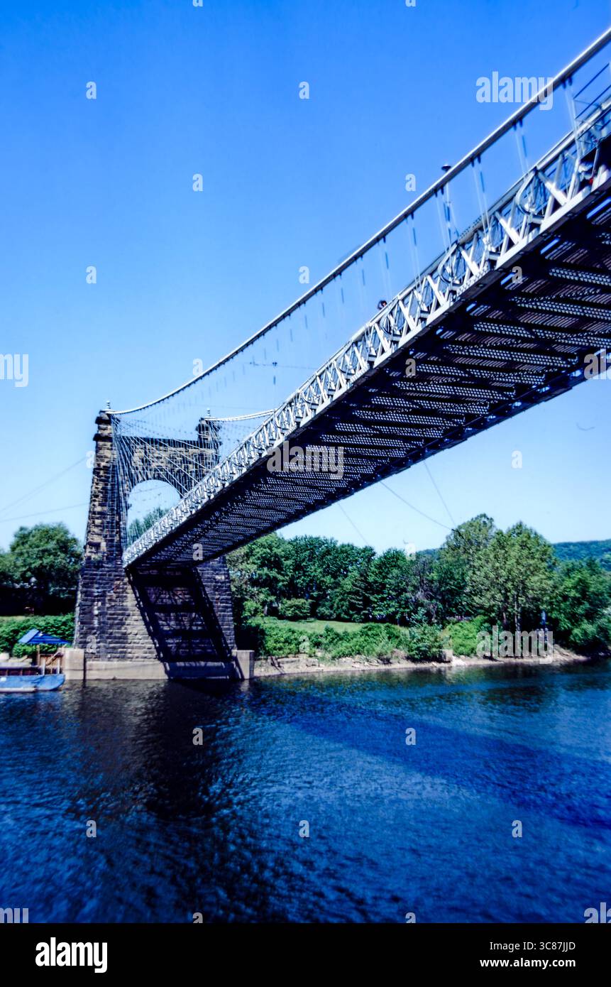 Angled underside view of vintage suspension bridge over a river with a ...