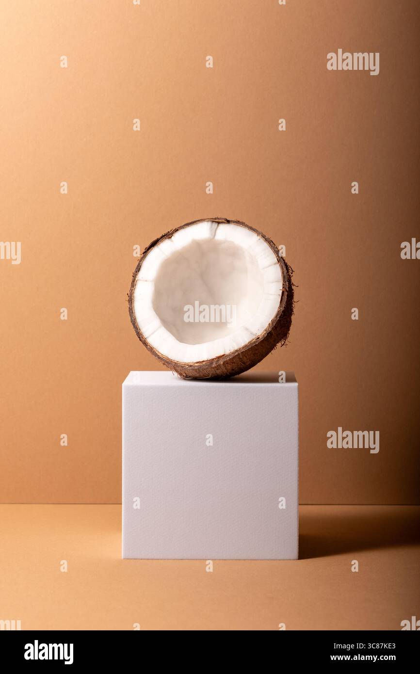 Cracked coconut on white stand. Minimal concept. Stock Photo