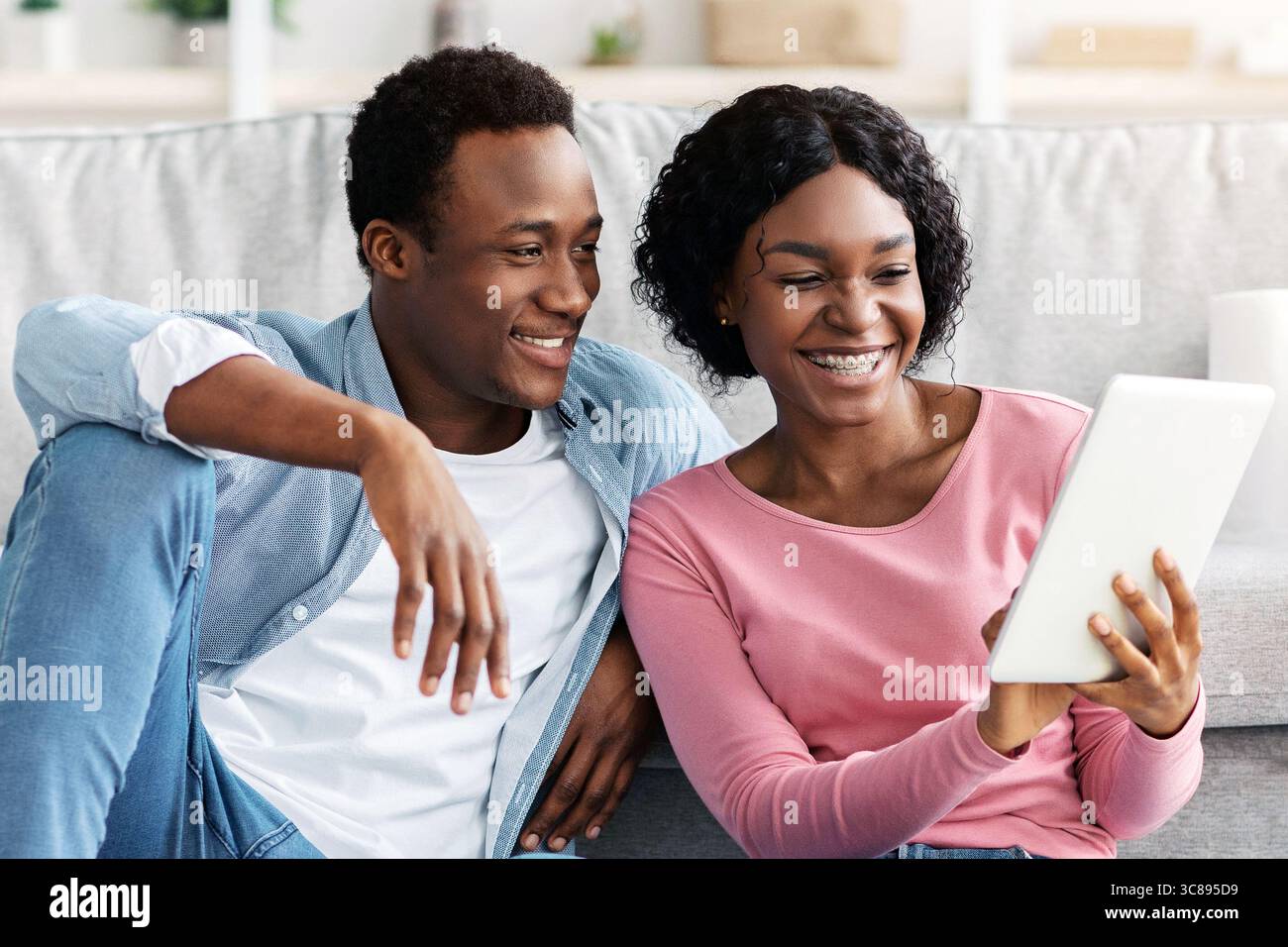 Black couple with cleaning tools resting, using digital tablet Stock Photo
