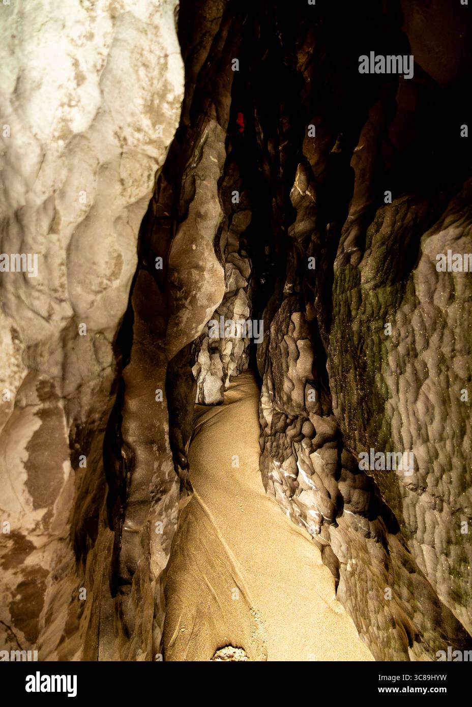 A view inside a cave, with a sandy path leading into the darkness. Stock Photo