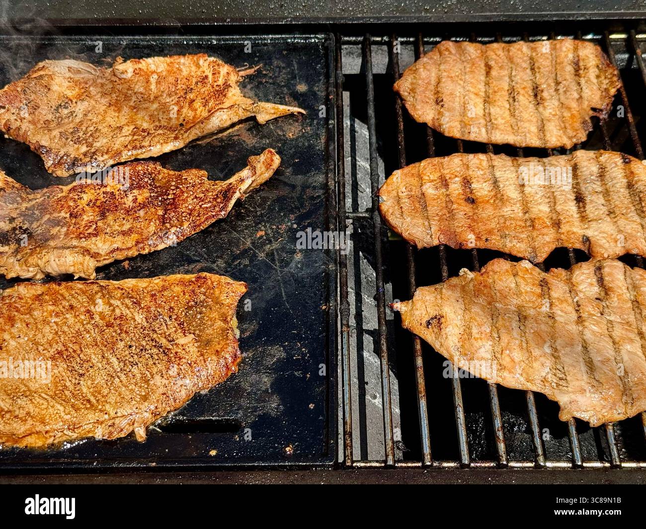 Seasoned pork steaks cooking on a barbecue grill during an outdoor cookout. - Smartphone Captured Stock Image