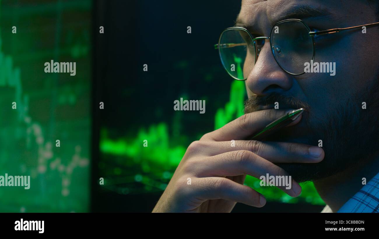 Indian Arabian man programmer coder hacker male guy trader IT specialist thoughtful analyst thinking analysing cryptocurrency financial chart graph Stock Photo