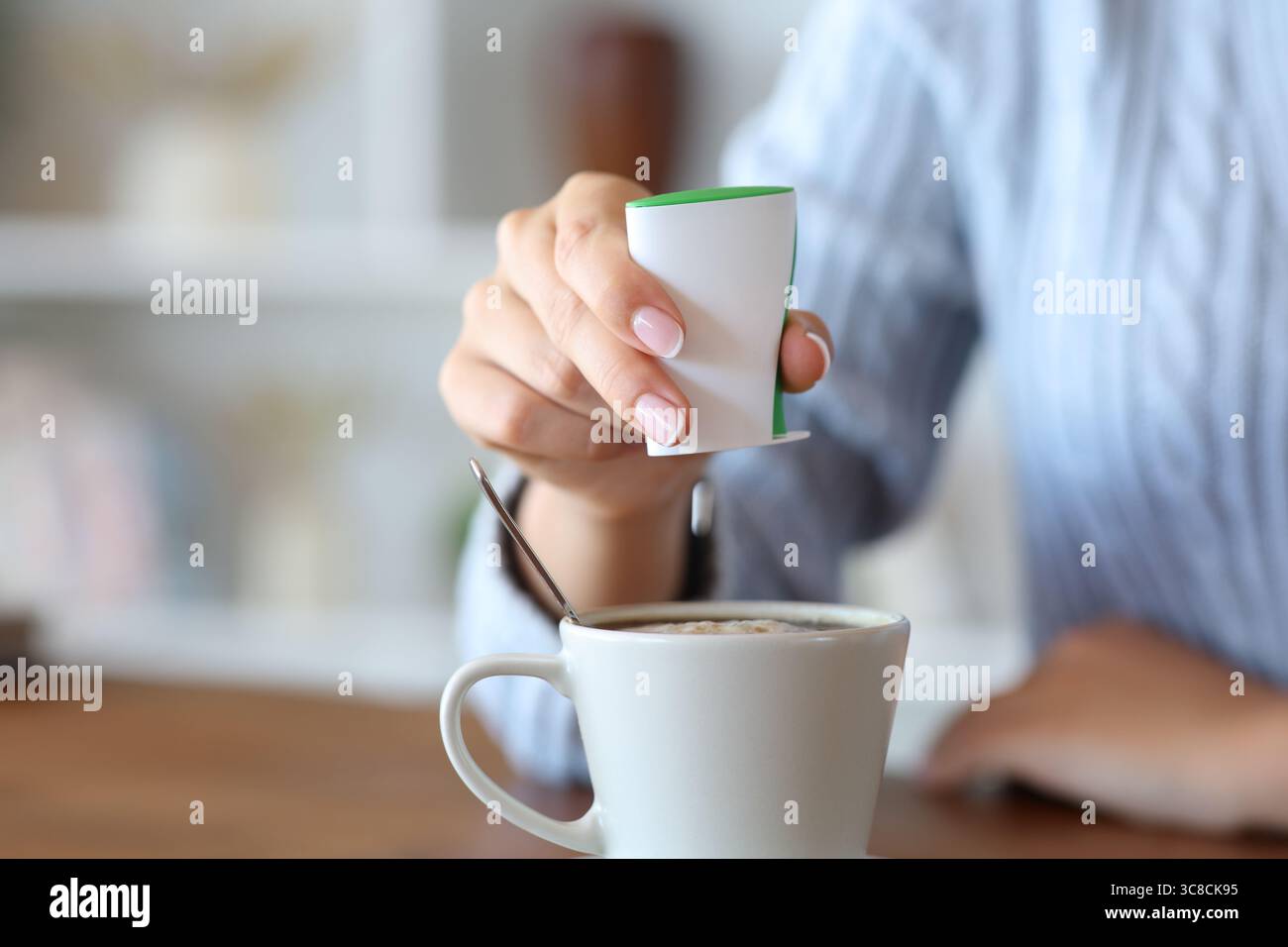Close up of a woman hand throwing saccharin on coffee at home Stock Photo