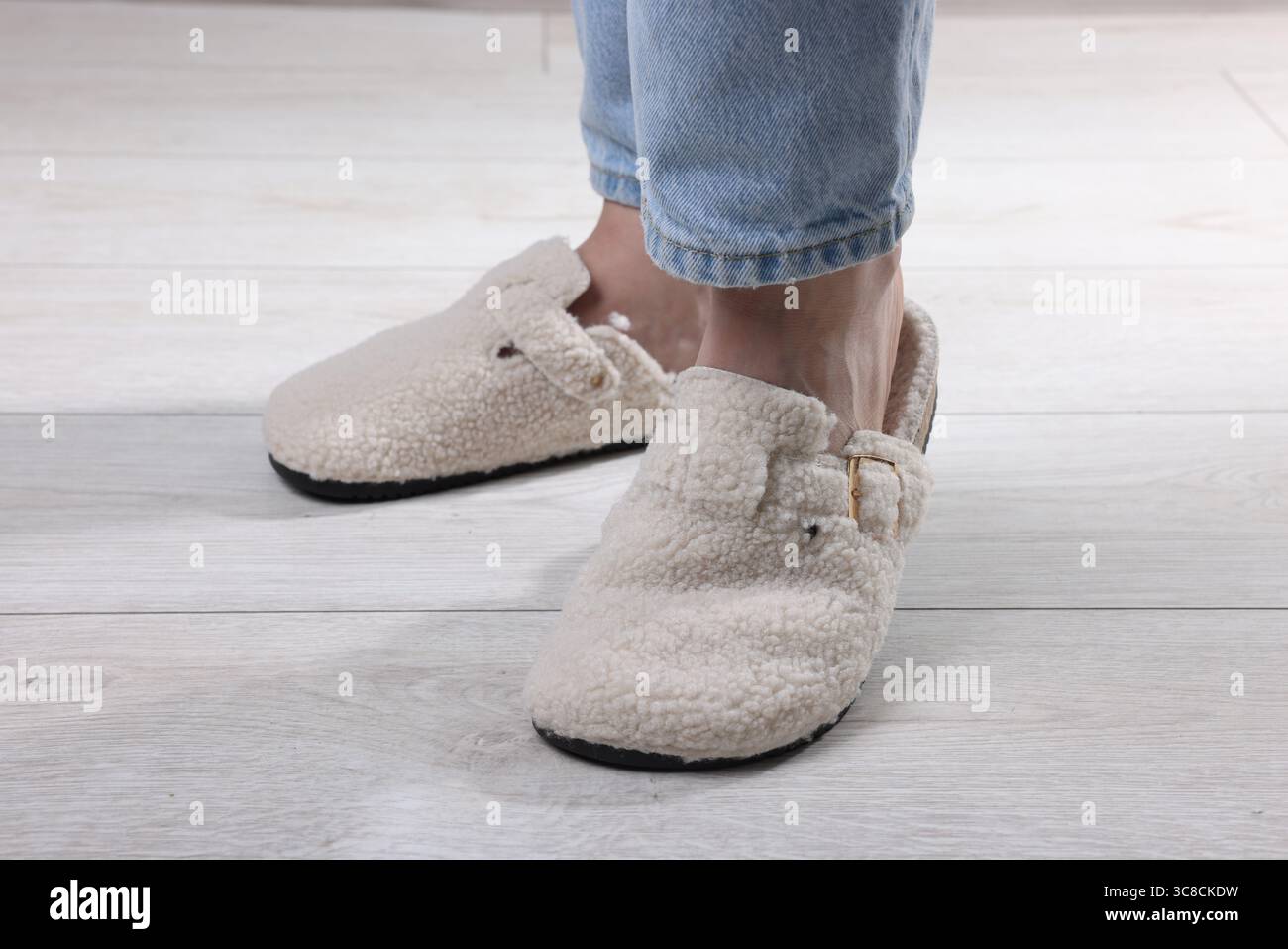 Woman In Soft White Slippers On Light Wooden Floor Closeup Stock Photo woman-in-soft-white-slippers-on-light-wooden-floor-closeup-stock-photo