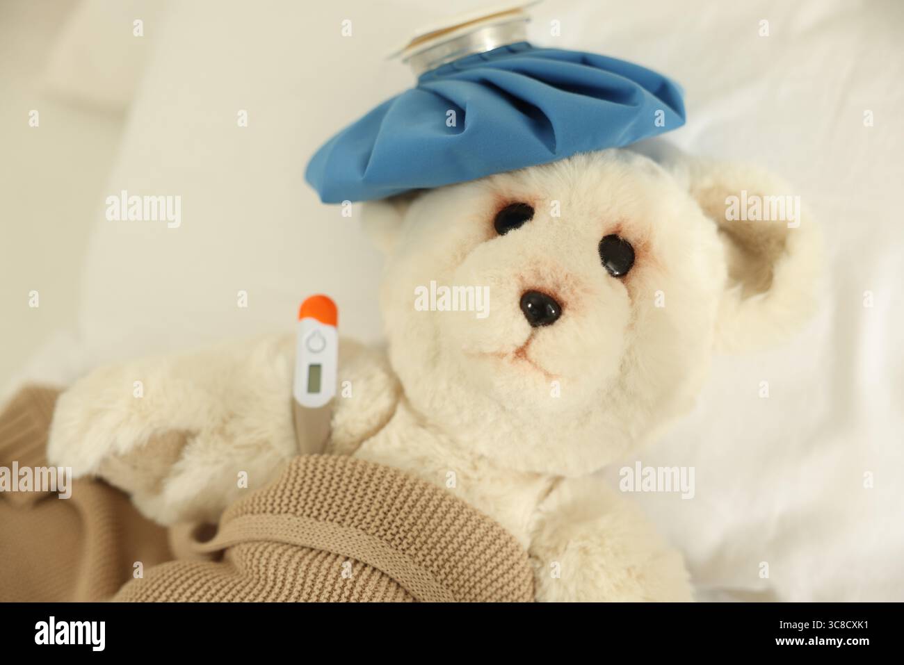 Pediatrics concept. Toy bear with ice bag and thermometer in bed Stock ...