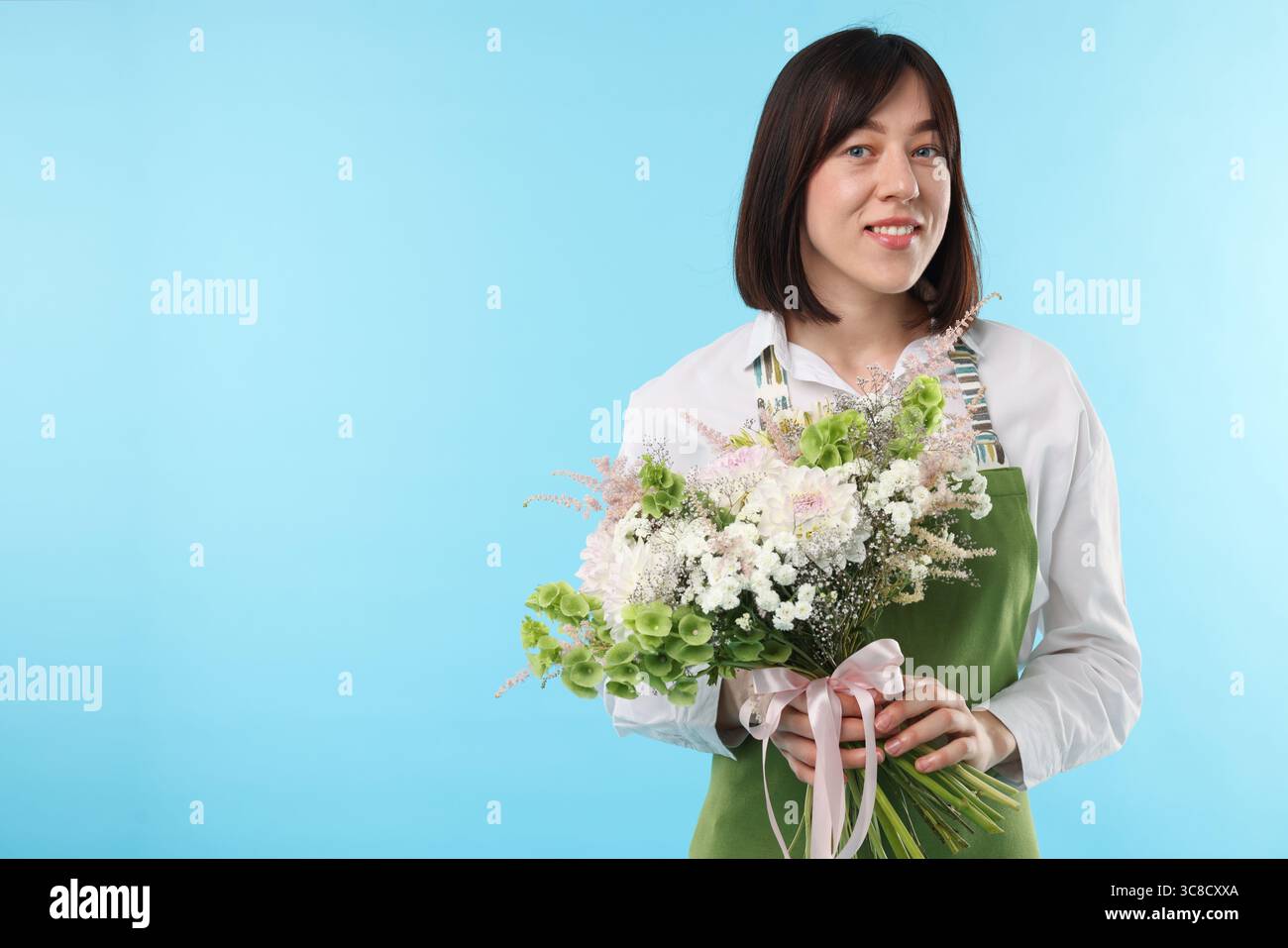 Florist with beautiful bouquet of flowers on light blue background ...