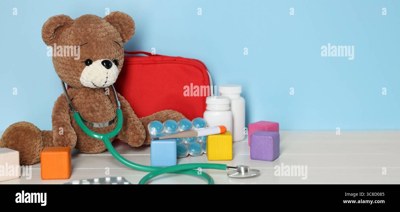 Pediatrician concept. Toy bear, cubes, first aid kit, pills and ...