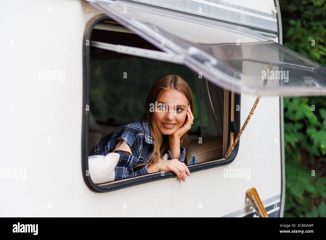 Woman looking out the window of a camper Stock Photo - Alamy
