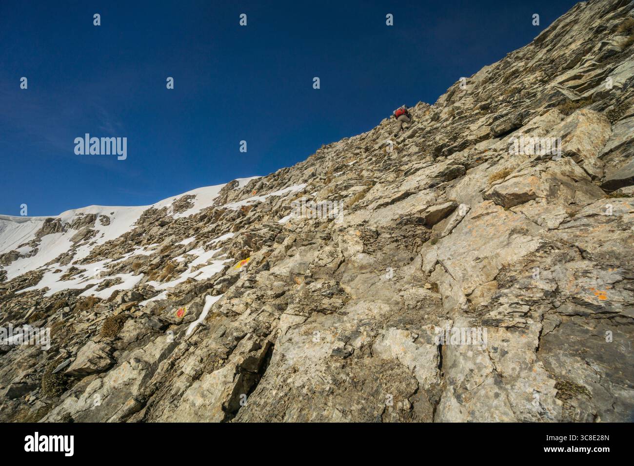 View of a rugged, rocky mountain slope with patches of snow under a clear blue sky, a challenging climb, Litochoro, Larisa, Greece. Stock Photo