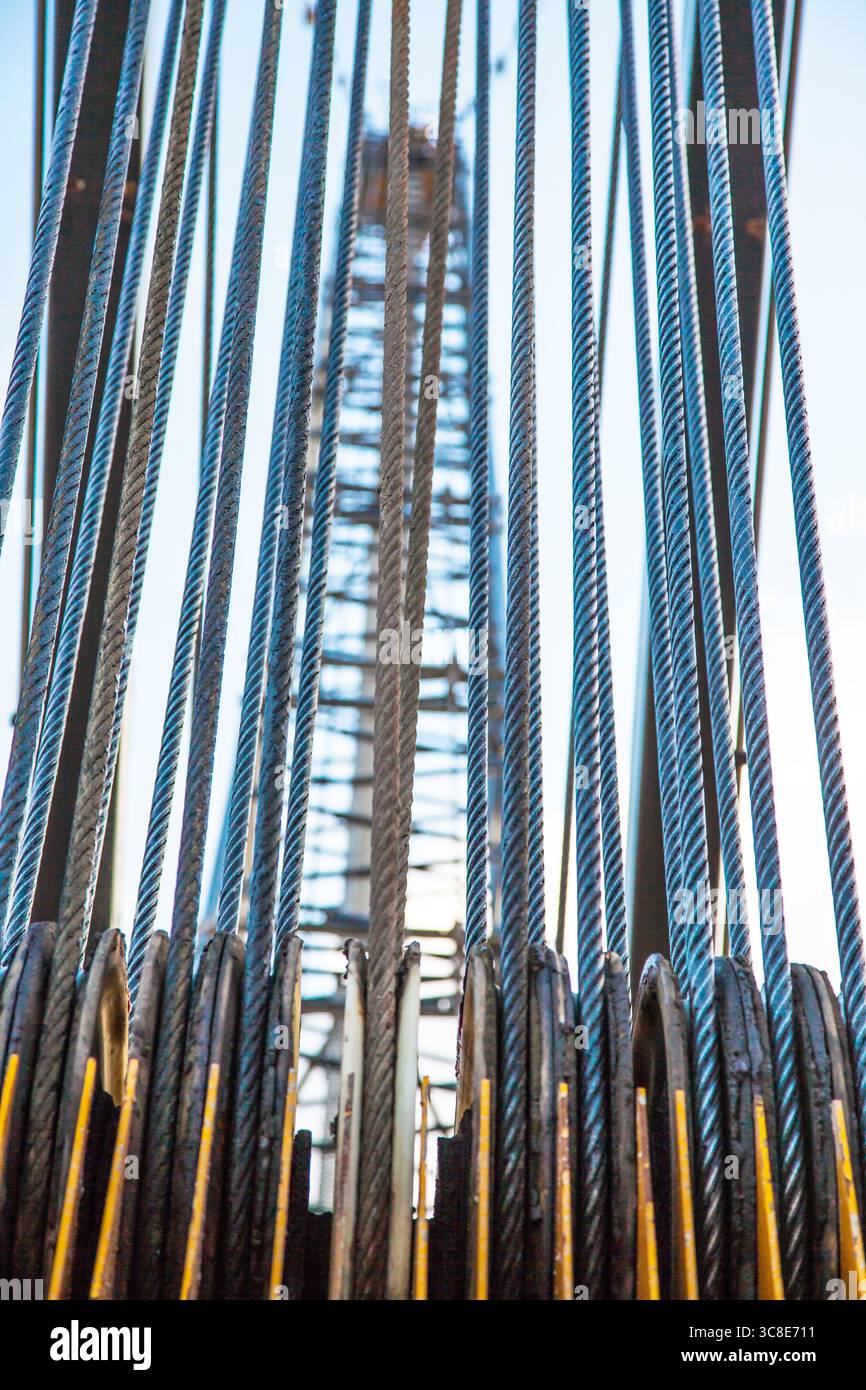 Stretched steel cables on the rollers of a cargo crane, close-up. Stock Photo