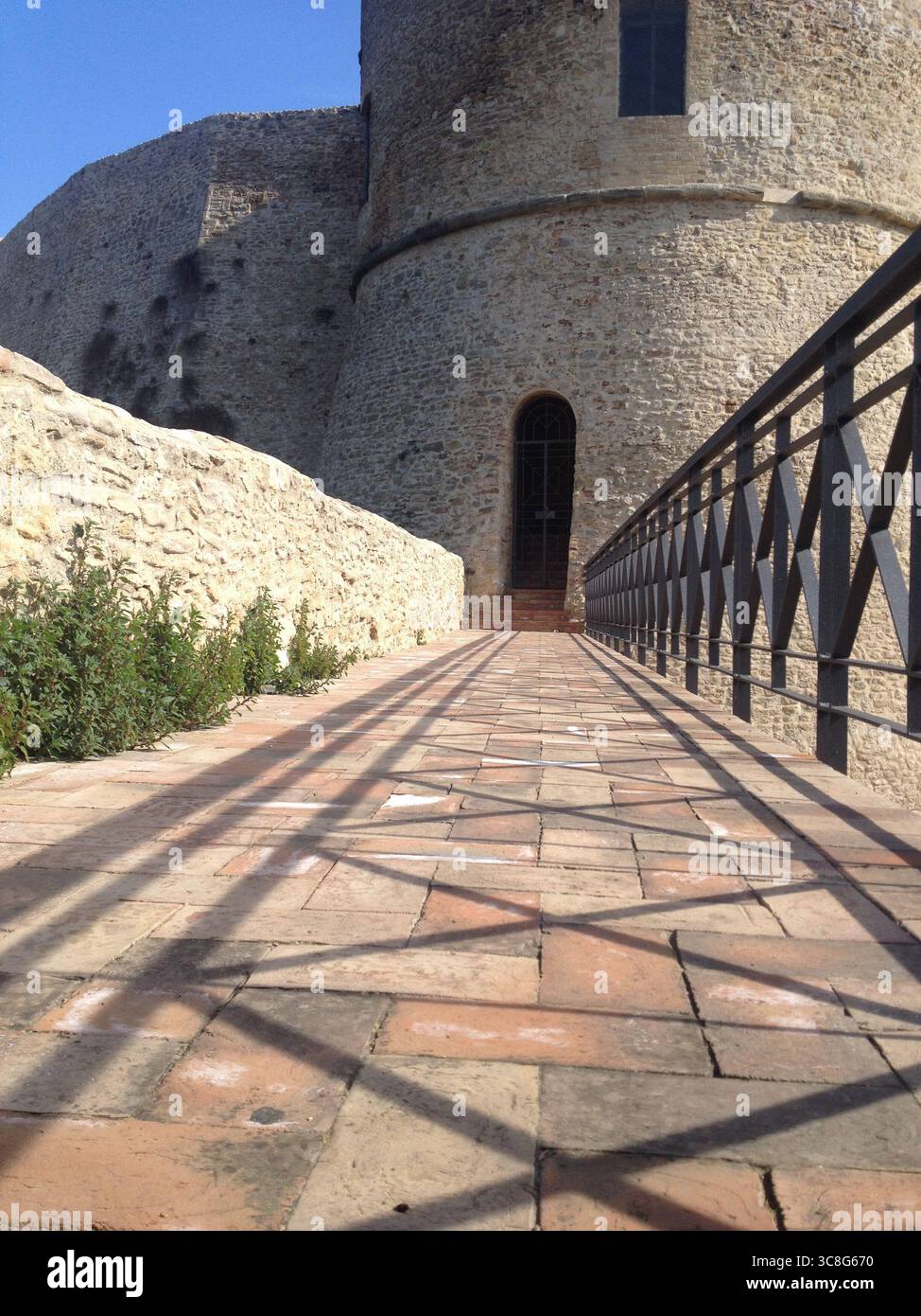 Metal railing guiding visitors along walkway toward historic Aragonese ...