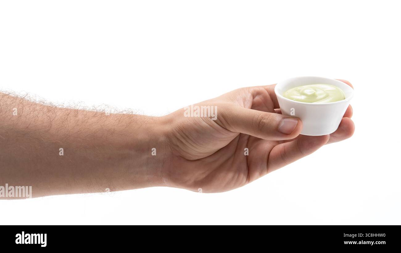Hand holding small cup of green sauce or dip Stock Photo