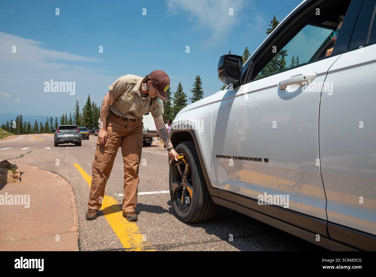 Colorado Springs, Colorado - A Pikes Peak ranger checks the temperature of brakes on a car descending 14,115' Pikes Peak. If the brakes have become ho Stock Photo