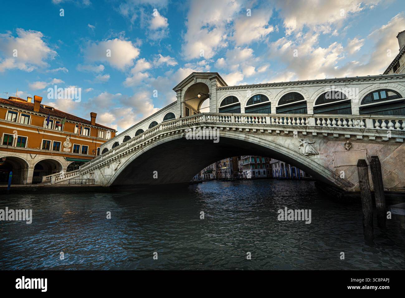 The iconic Rialto Bridge spanning the Grand Canal in Venice, bathed in golden evening light. Stock Photo