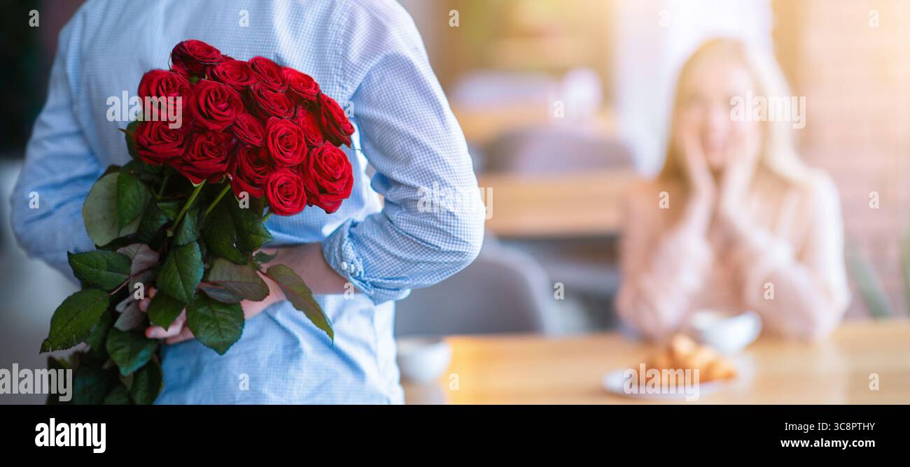 Man Getting Roses Romantic young guy with bouquet of red roses behind his back making ...