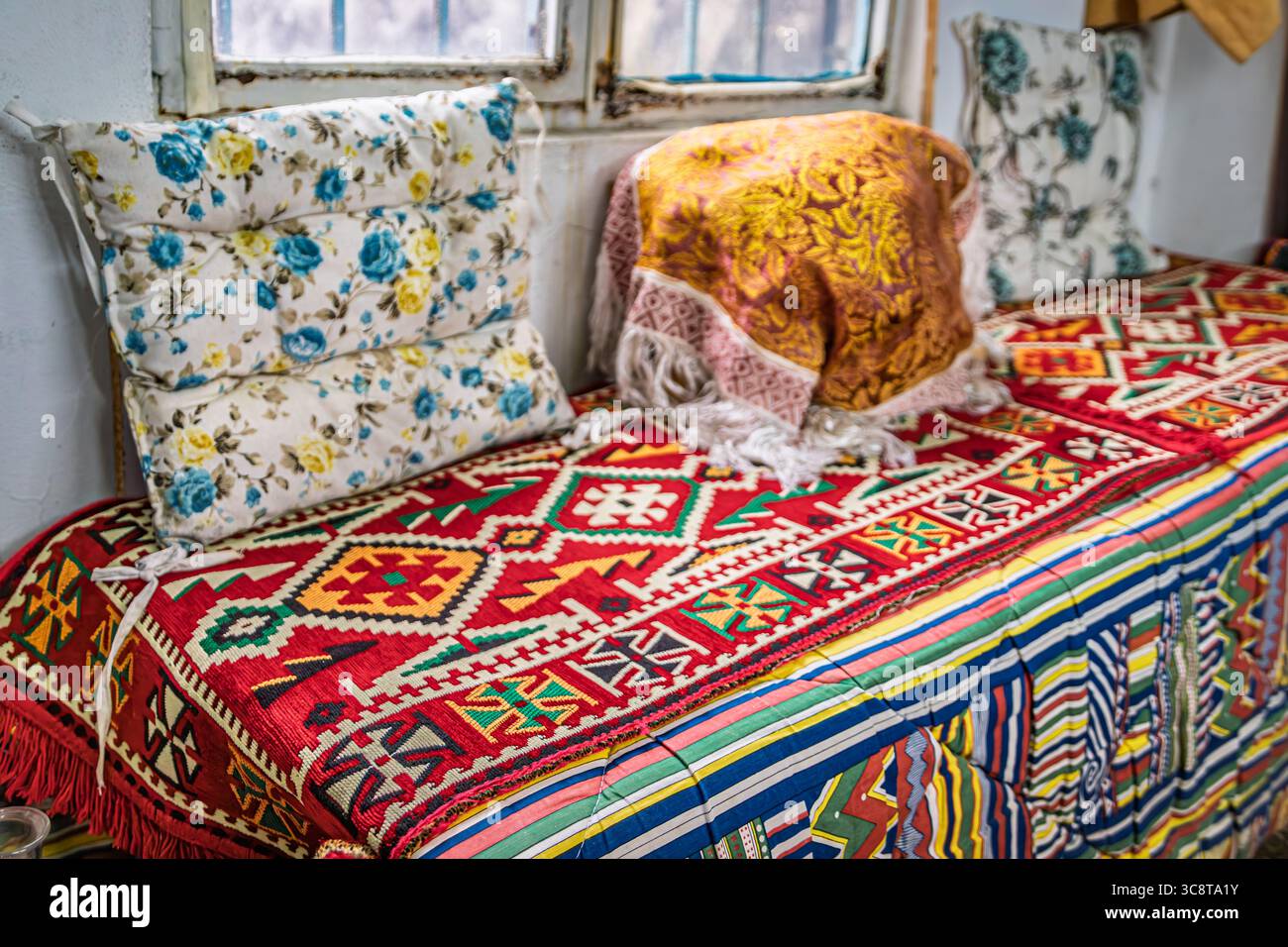 Traditional Turkish divan covered in a vibrant kilim pattern fabric with floral pillows, behind-the-scenes workshop, Grand Bazaar in Istanbul, Turkey Stock Photo