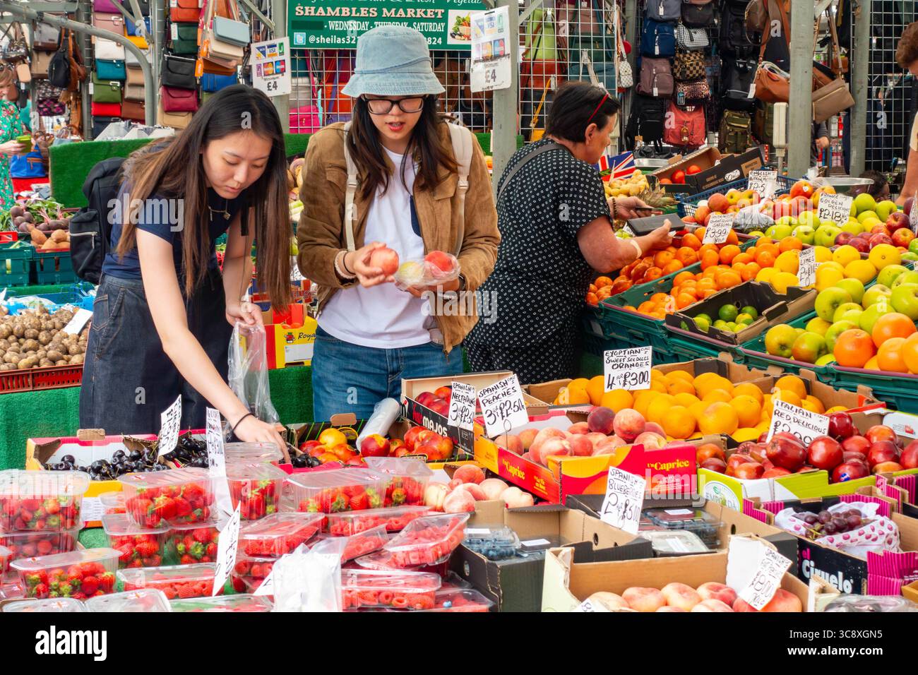 A couple of ladies choosing fruit at a greengrocer's stall in The Shambles Market in York, UK Stock Photo