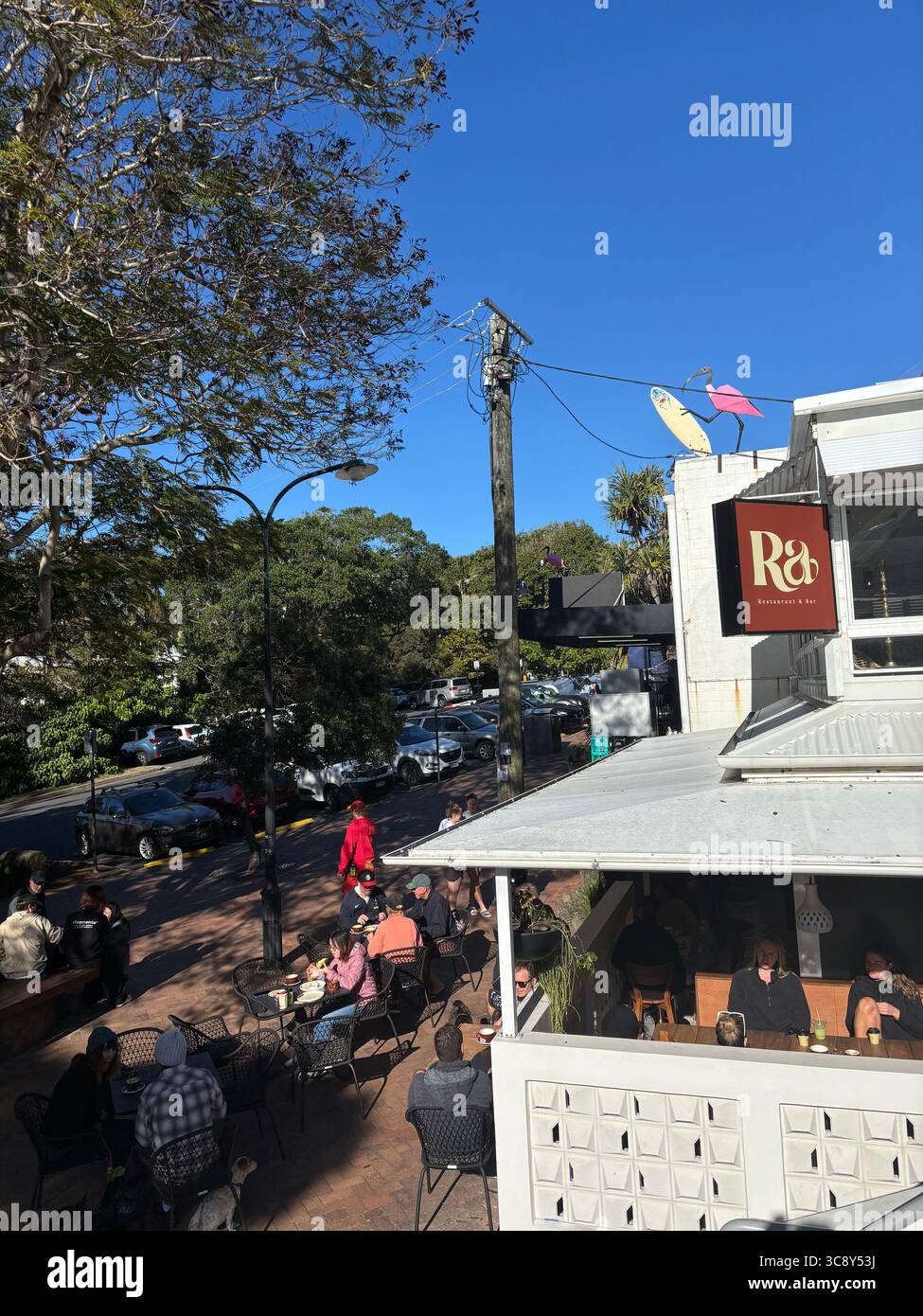 People sitting at outdoor tables at cafe on a winter morning, Sunshine Beach, Queensland, Australia. no MR or PR - Smartphone Captured Stock Image