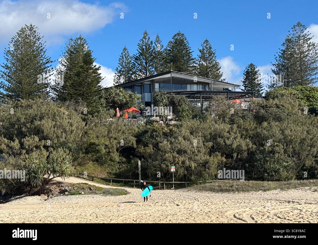 Man with surfboard on beach at Sunshine Beach Surf Club, Sunshine Coast, Queensland, Australia. No MR or PR - Smartphone Captured Stock Image