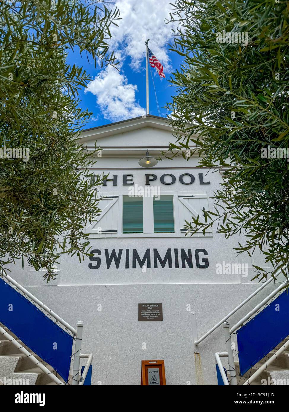 Vintage swimming pool signage to entrance of hot spring pool surrounded by greenery - Smartphone Captured Stock Image