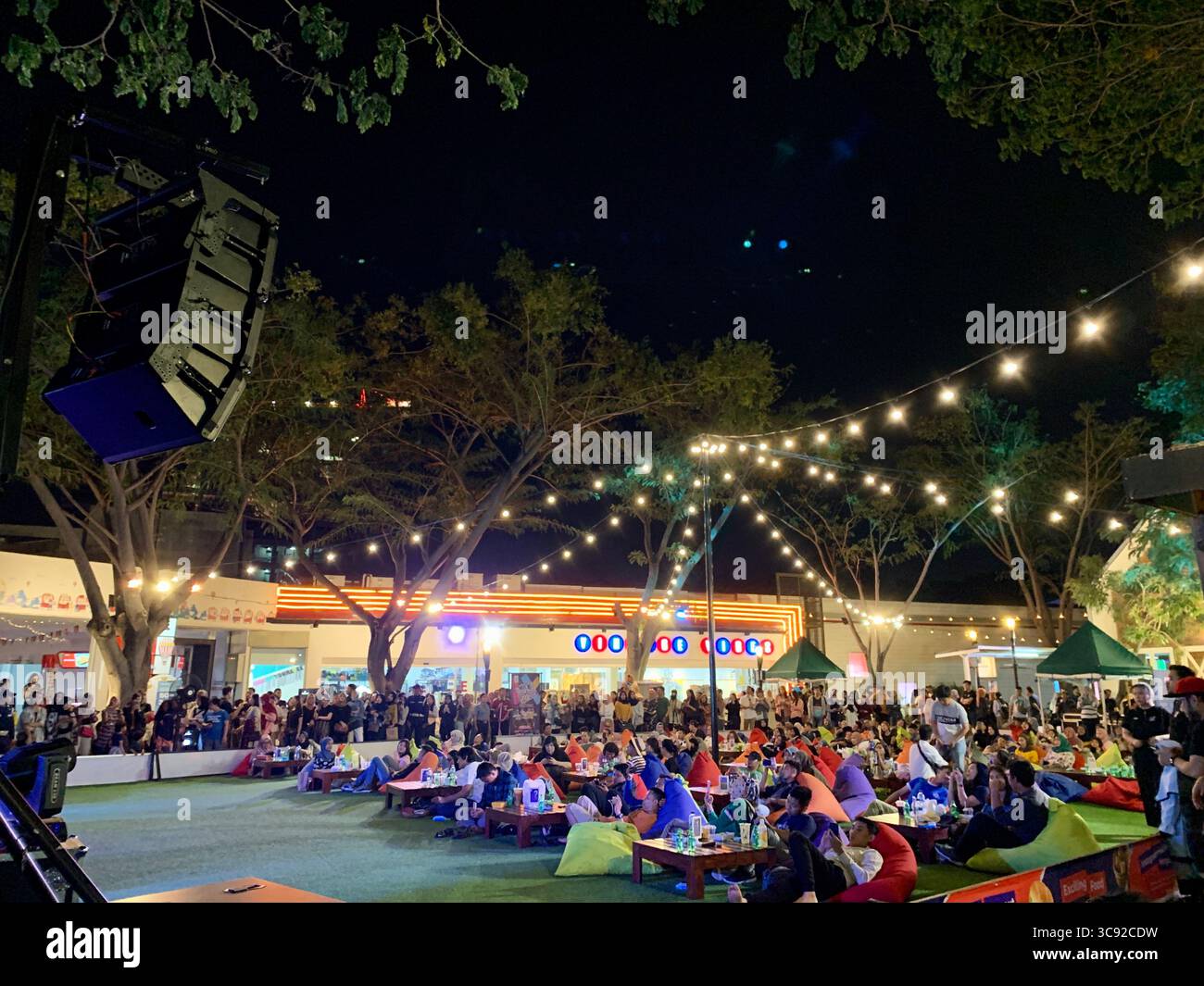 Crowd at outdoor evening event under string lights. - Smartphone Captured Stock Image