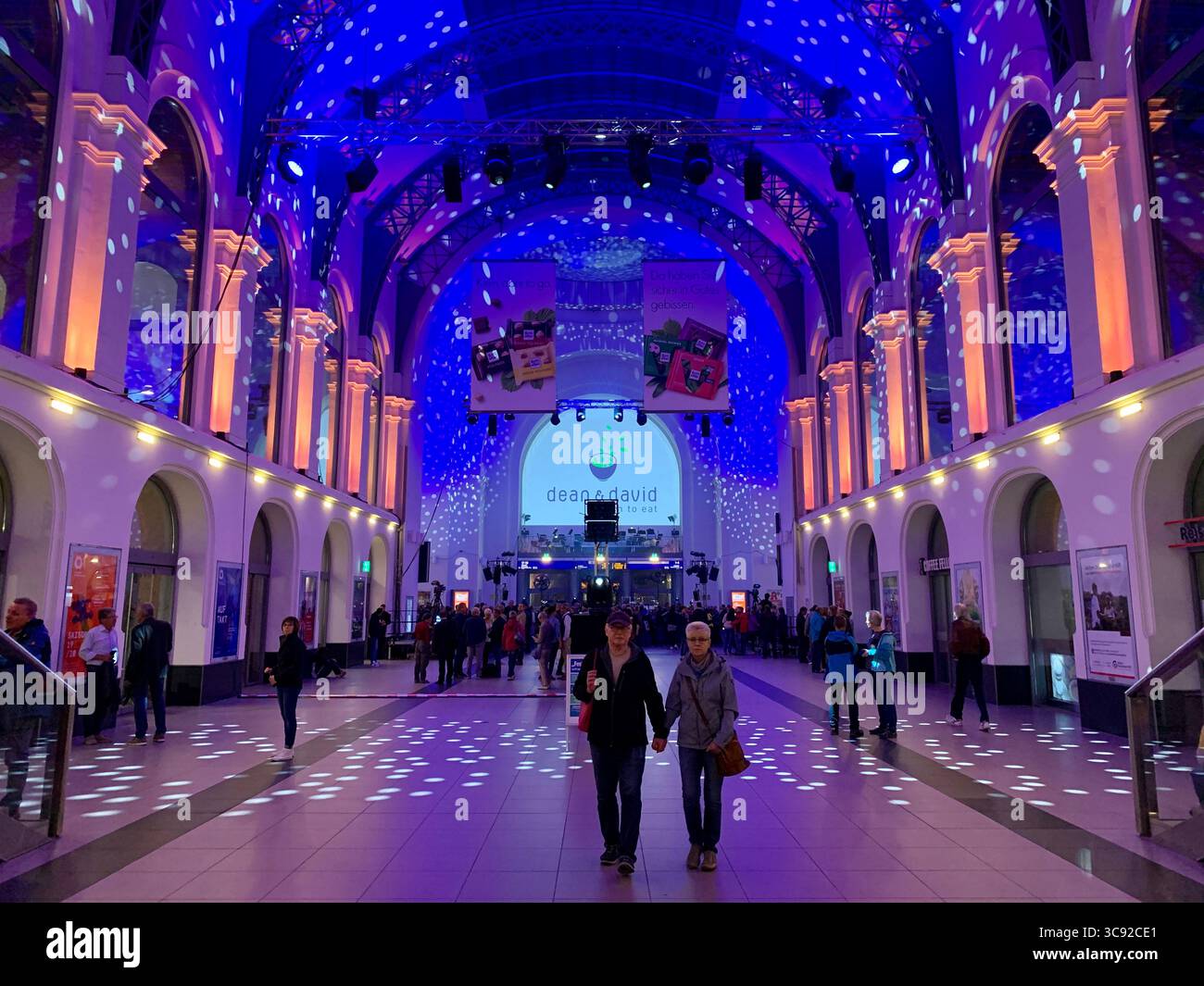 Visitors inside a blue-lit public event hall. - Smartphone Captured Stock Image