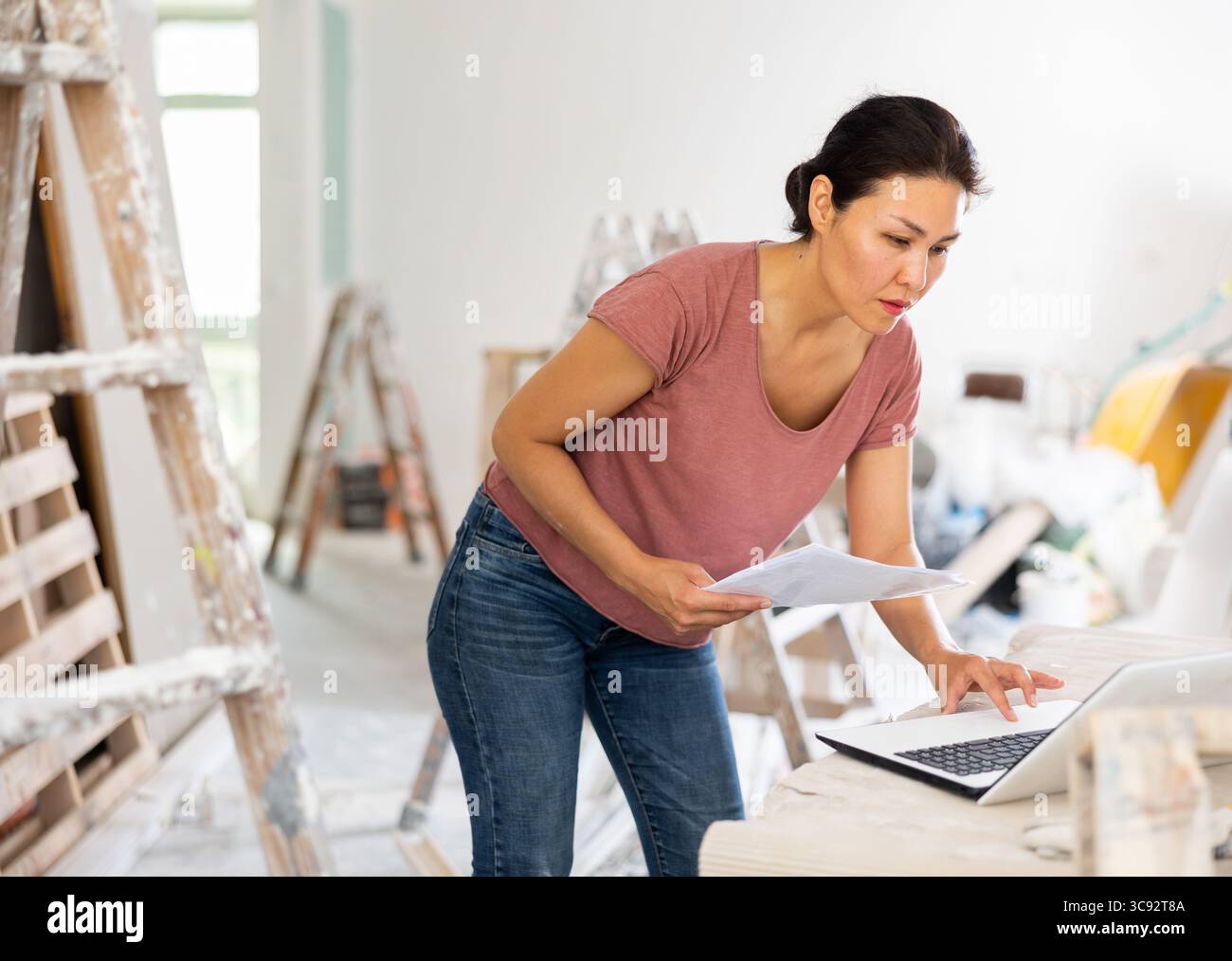 Woman construction manager checking project documentation, using laptop Stock Photo