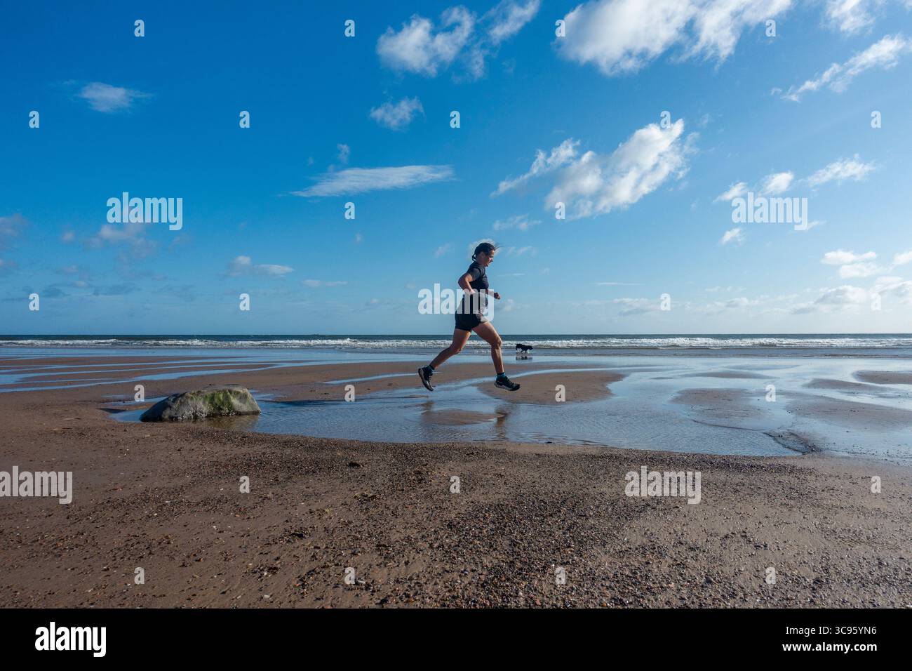 Middle aged woman jogging, running on beach Stock Photo