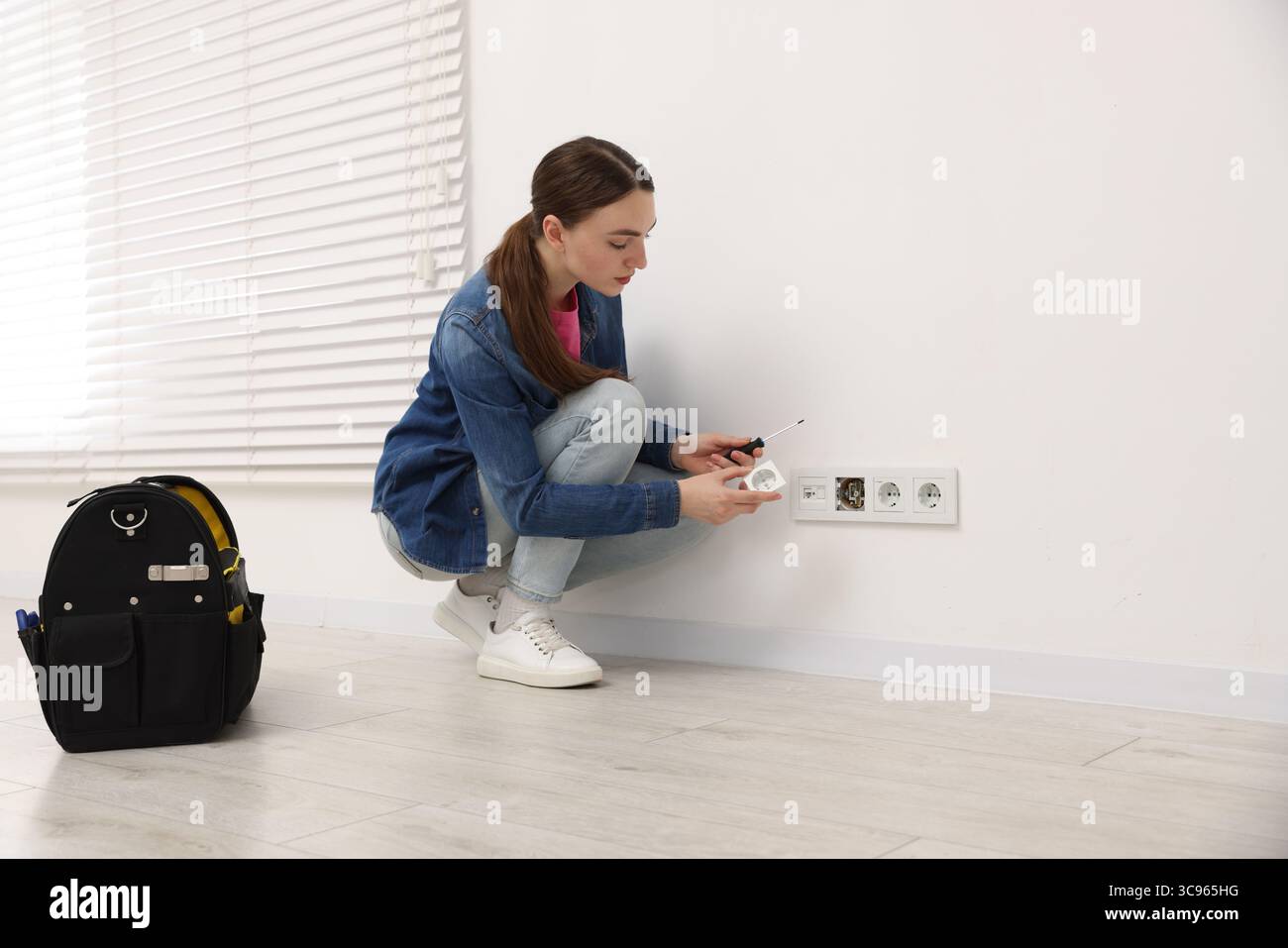 Woman with screwdriver installing new socket at home Stock Photo