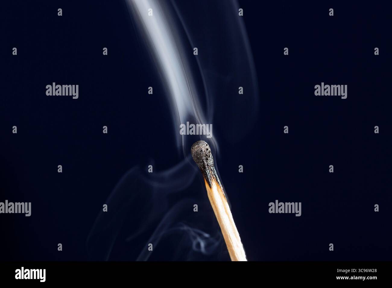 Extinguished match close up with smoke on dark blue background Stock Photo