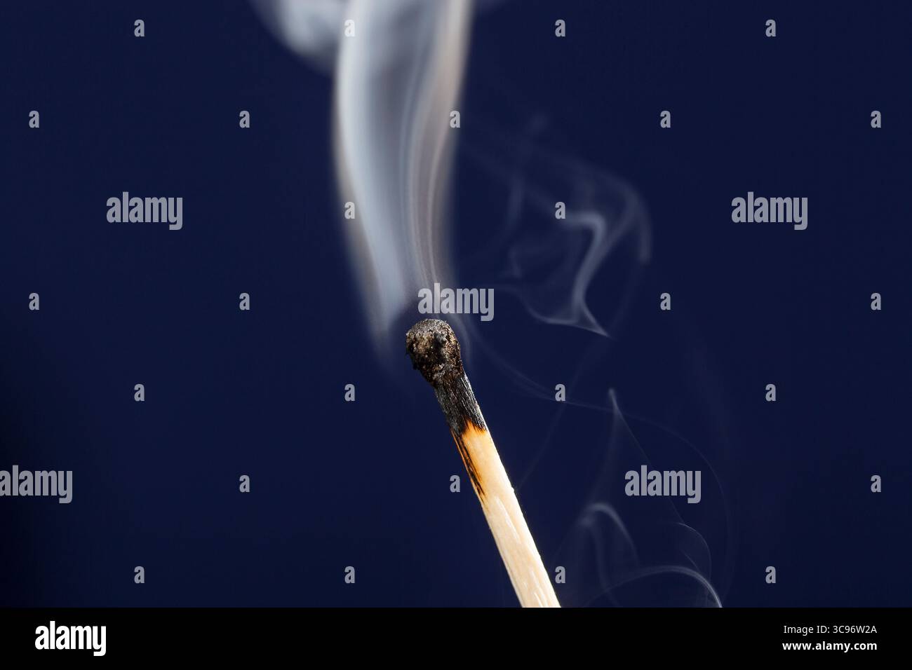 Extinguished match close up with smoke on dark blue background Stock Photo
