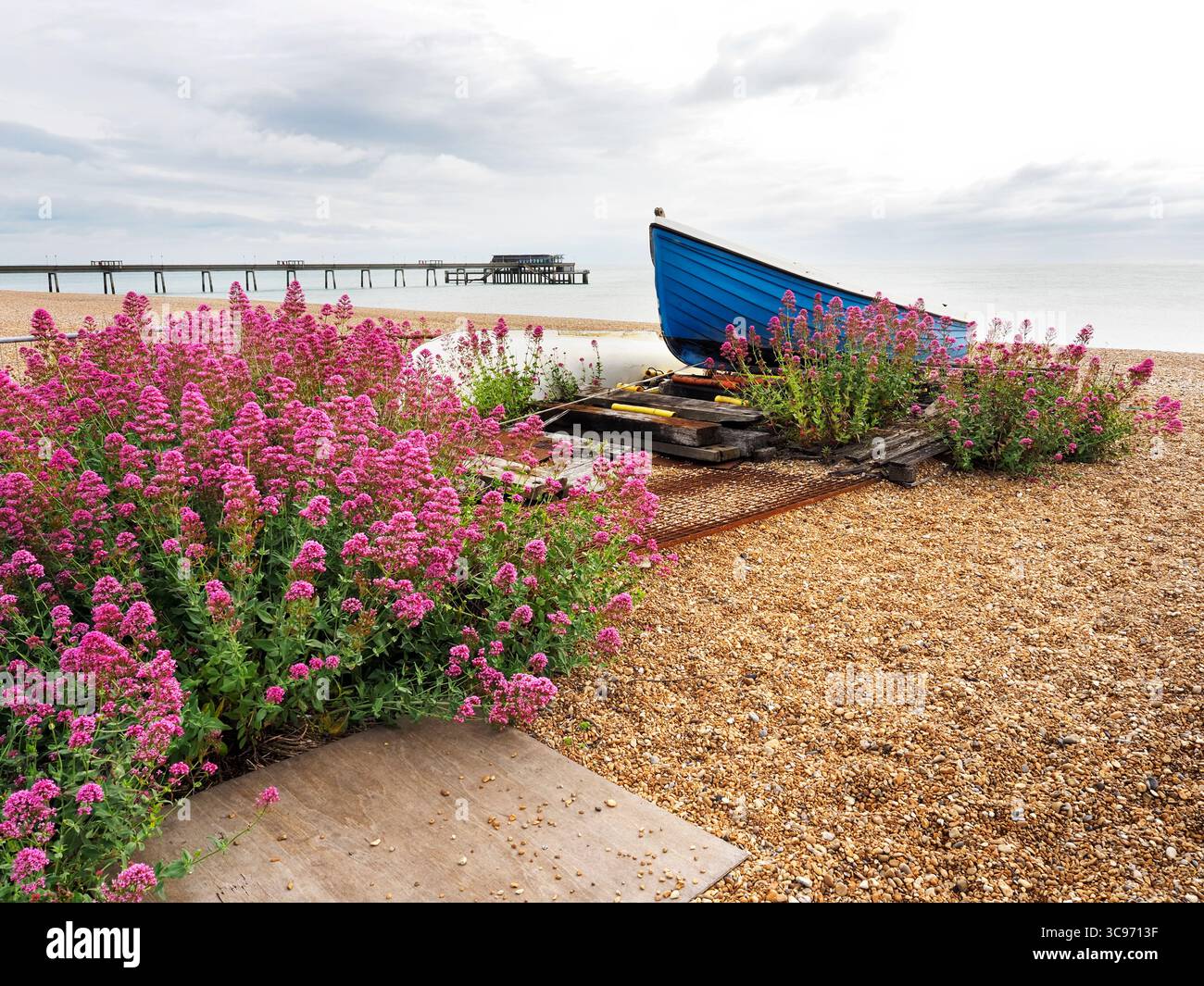 Boat on the shingle beach with Deal Pier in the distance at Deal in Kent England Stock Photo