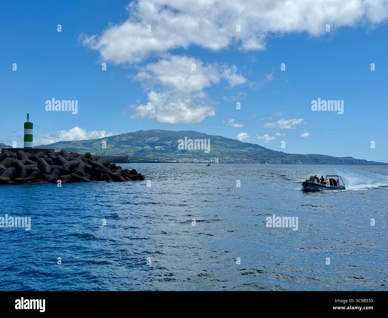 Tourist speedboat returning to Ponta Delgada marina after a diving trip, with the volcanic mountain of Lagoa do Fogo in the background, São Miguel Isl - Smartphone Captured Stock Image
