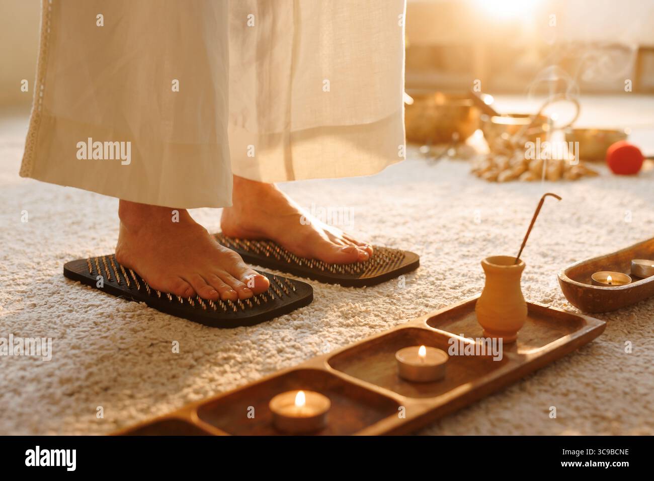 Barefoot standing on sadhu board with nails for acupressure, mindfulness, pain relief, and home meditation ritual Stock Photo