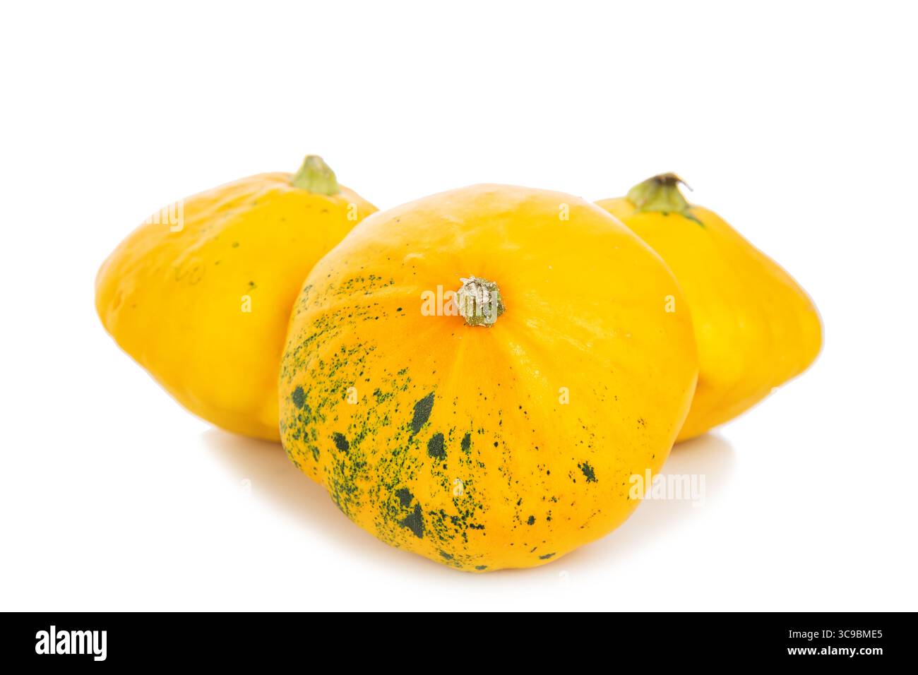 Three yellow bush pumpkins isolated on a white background. Stock Photo