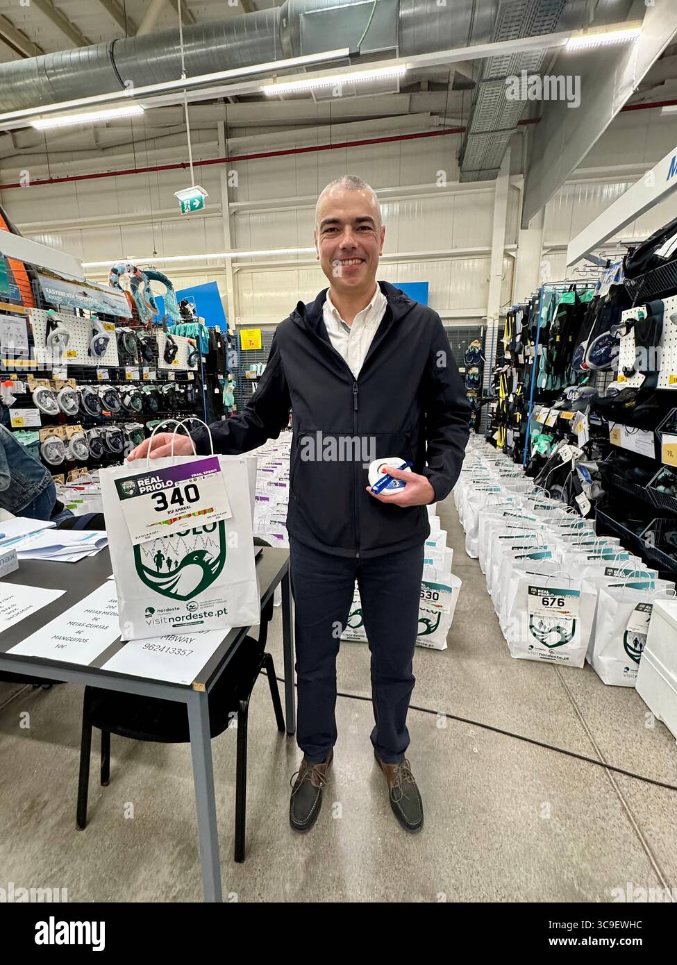 Participants receiving race bibs and swag bags during registration for the Trail Real Priolo running event held in the Azores, Portugal. - Smartphone Captured Stock Image