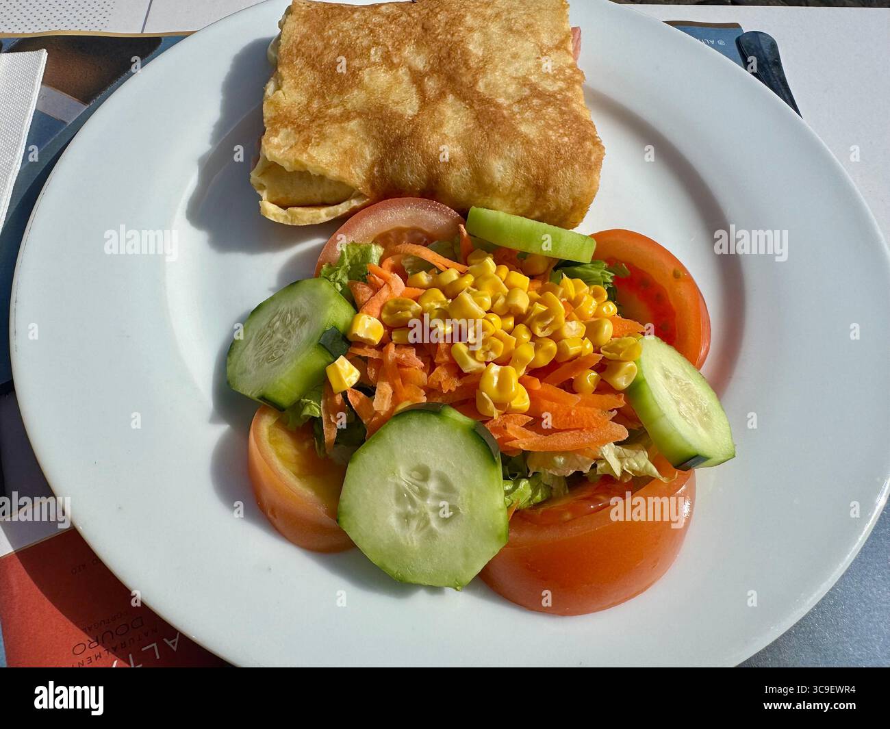 Fresh vegetable salad with tomato, cucumber, corn, carrot, and a fried pastry on a white plate. - Smartphone Captured Stock Image